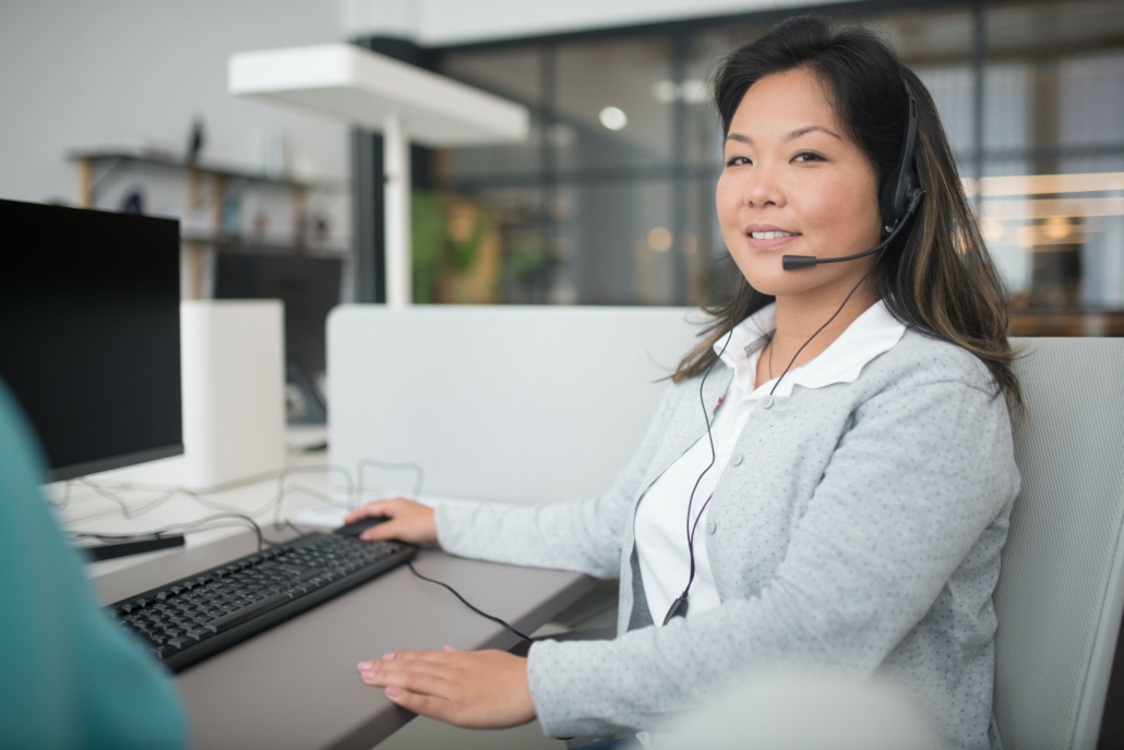Mitarbeiterin mit Headset arbeitet an einem Computerarbeitsplatz.